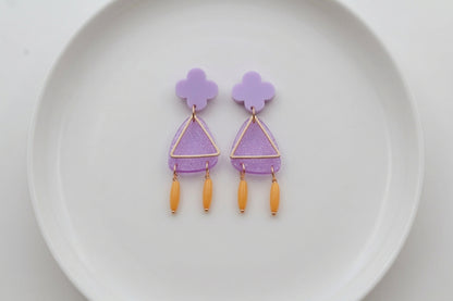 Purple Maud flower statement earrings arranged on a white plate