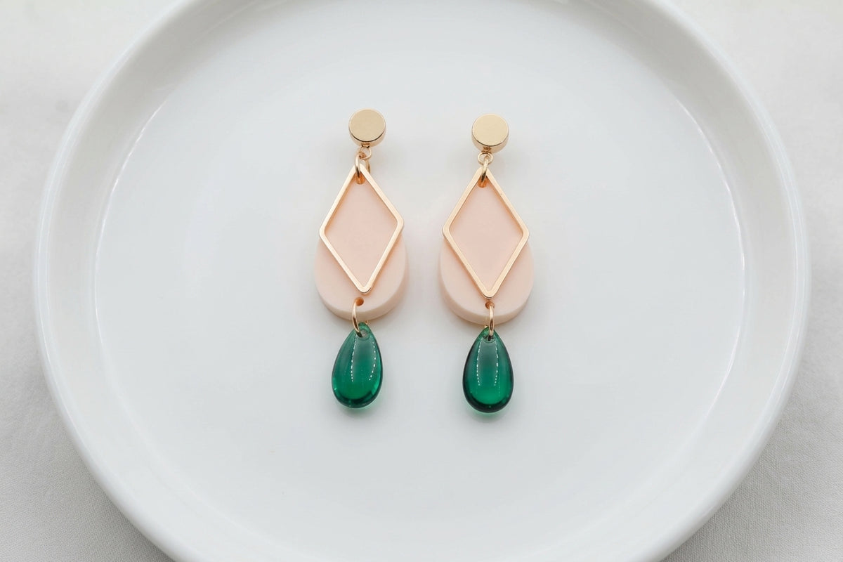 Beige Mia geometric teardrop earrings arranged on a white plate