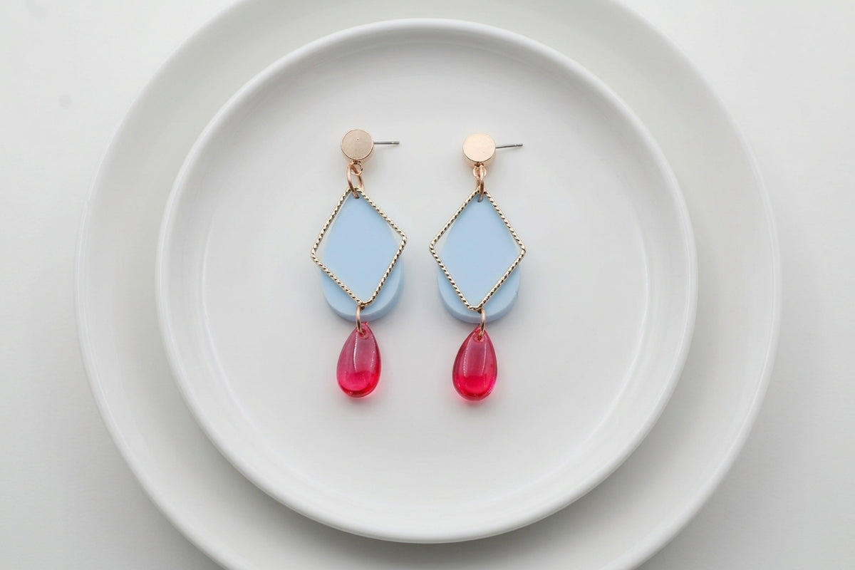 Blue Mia geometric teardrop earrings arranged on a white plate