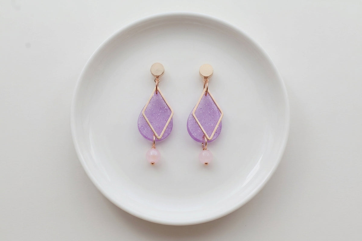 Purple Mia geometric teardrop earrings arranged on a white plate