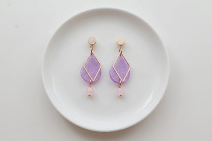 Purple Mia geometric teardrop earrings arranged on a white plate