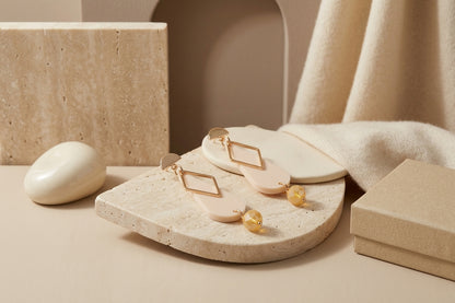 Beige Mila teardrop statement earrings in a styled product setting