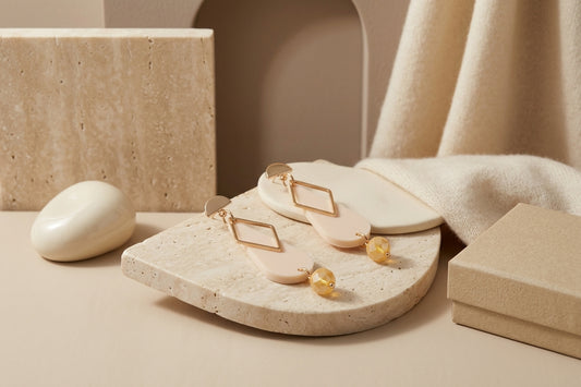 Beige Mila teardrop statement earrings in a styled product setting