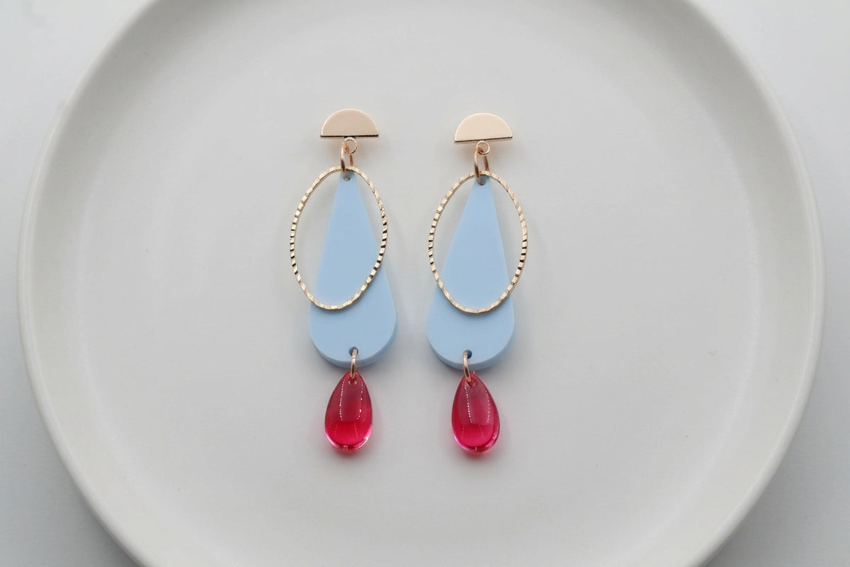 Blue Mila teardrop statement earrings arranged on a white plate