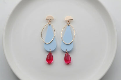 Blue Mila teardrop statement earrings arranged on a white plate