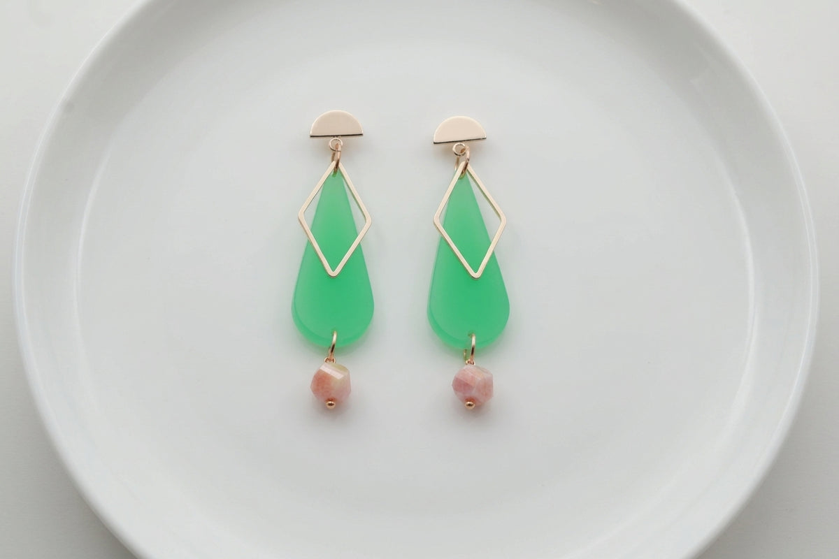Green Mila teardrop statement earrings arranged on a white plate