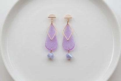 Purple Mila teardrop statement earrings arranged on a white plate