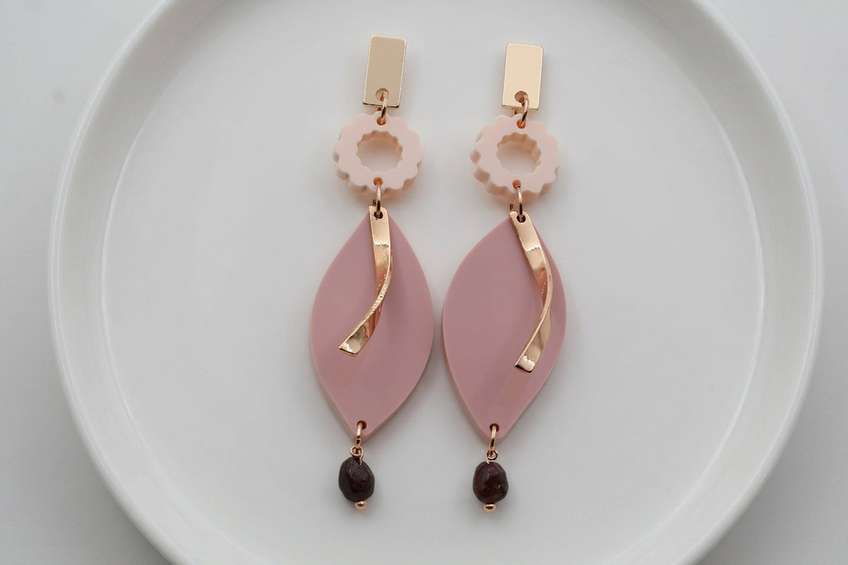 Beige Nia long geometric statement earrings arranged on a white plate