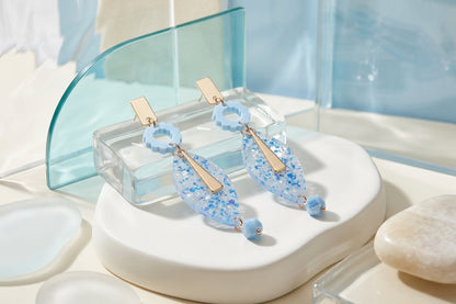 Blue Nia long geometric statement earrings in a styled product setting