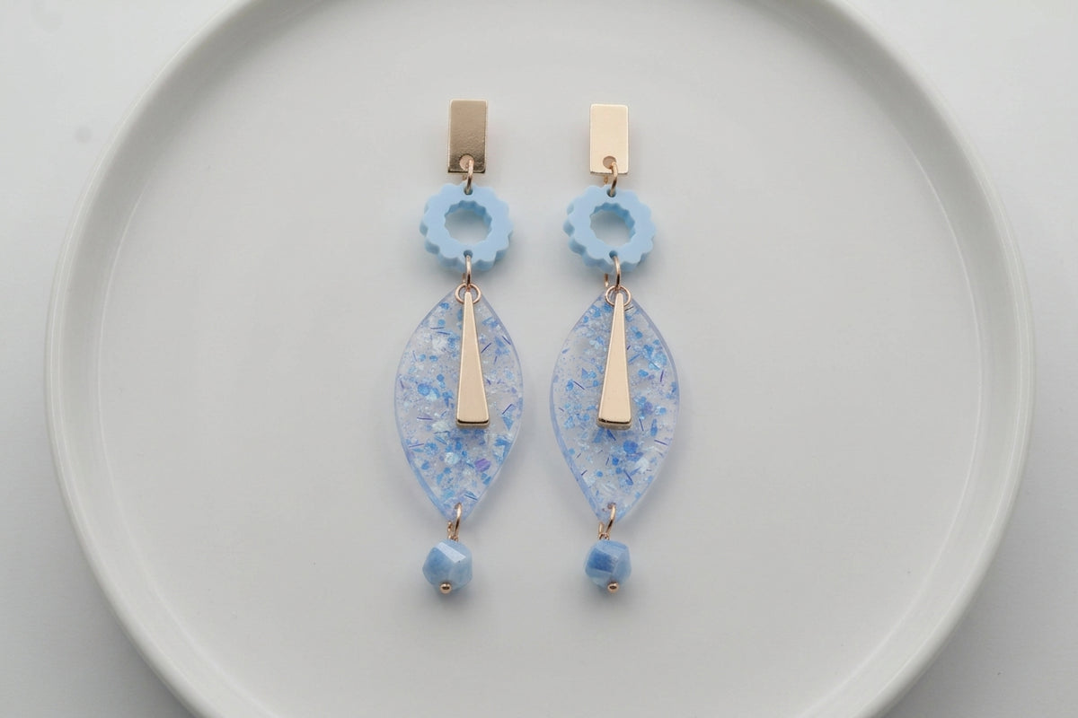 Blue Nia long geometric statement earrings arranged on a white plate
