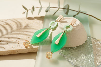 Green Nia long geometric statement earrings in a styled product setting