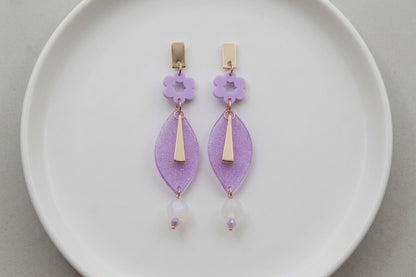 Purple Nia long geometric statement earrings arranged on a white plate