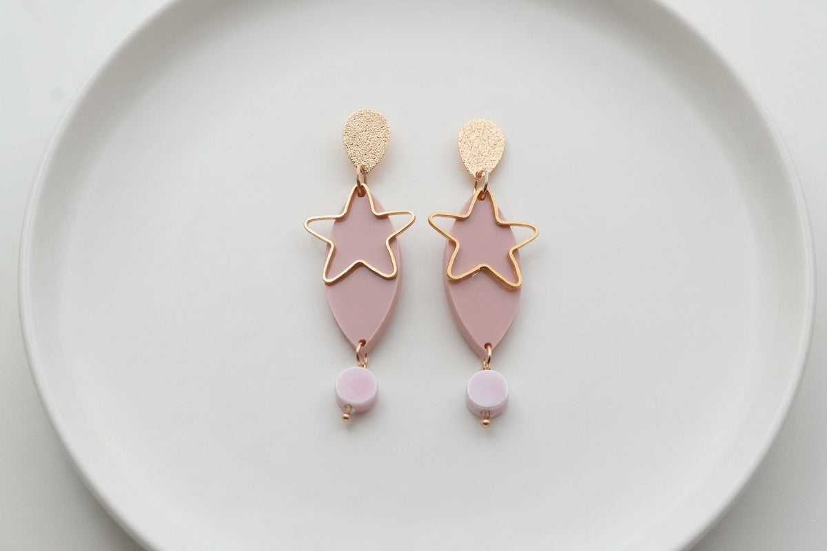 Beige Nina star geometric dangle earrings arranged on a white plate