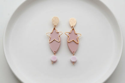 Beige Nina star geometric dangle earrings arranged on a white plate