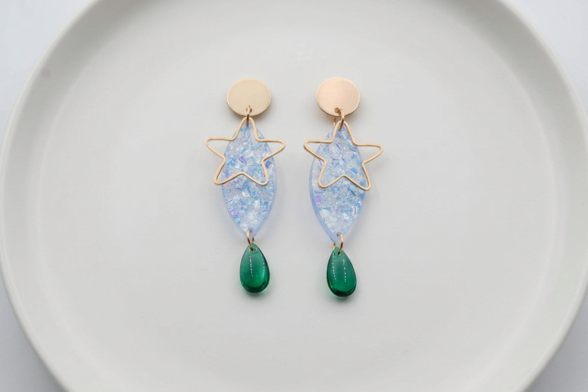 Blue Nina star geometric dangle earrings arranged on a white plate