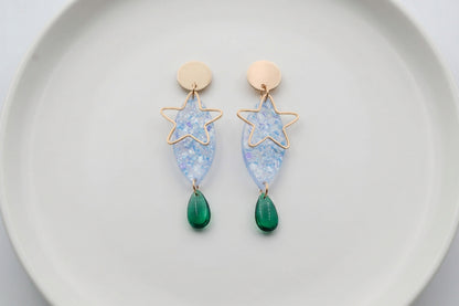 Blue Nina star geometric dangle earrings arranged on a white plate