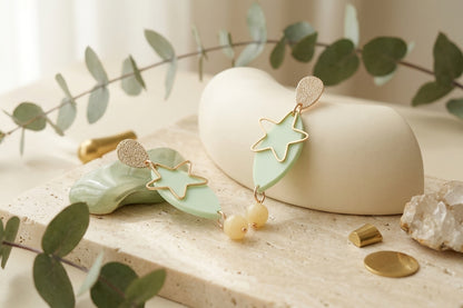 Green Nina star geometric dangle earrings in a styled product setting