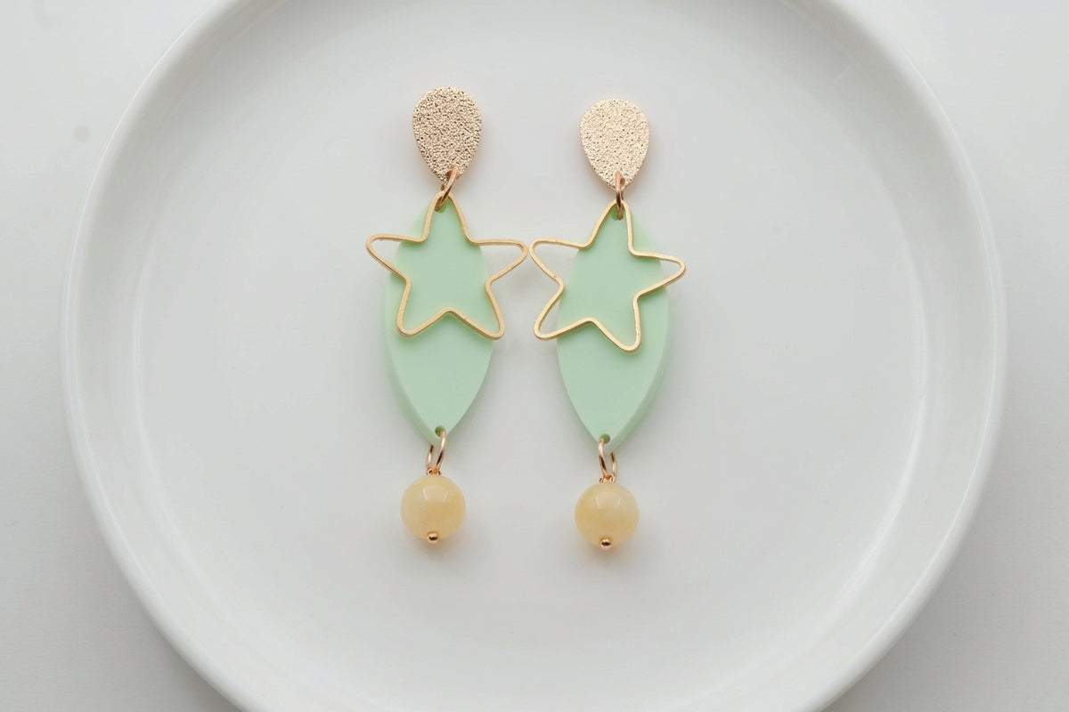 Green Nina star geometric dangle earrings arranged on a white plate