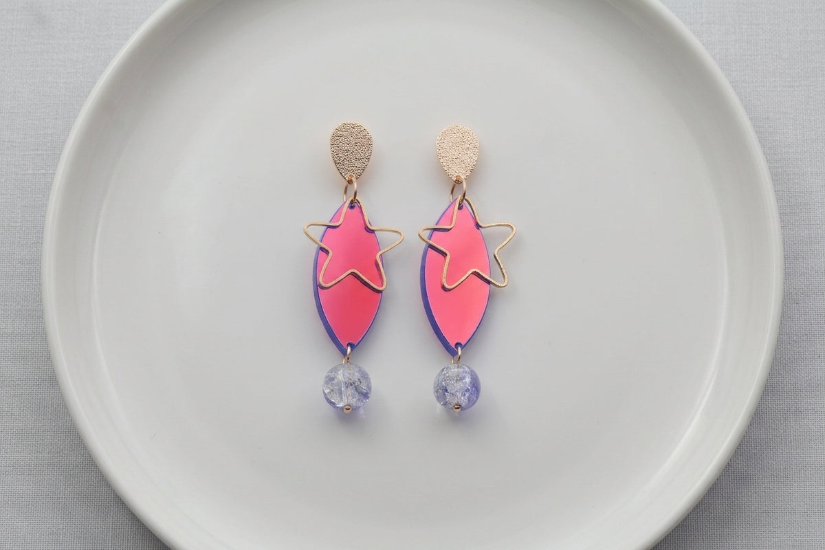 HB Nina star geometric dangle earrings arranged on a white plate
