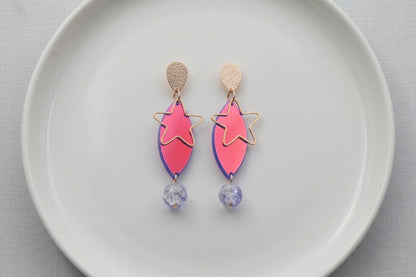 HB Nina star geometric dangle earrings arranged on a white plate