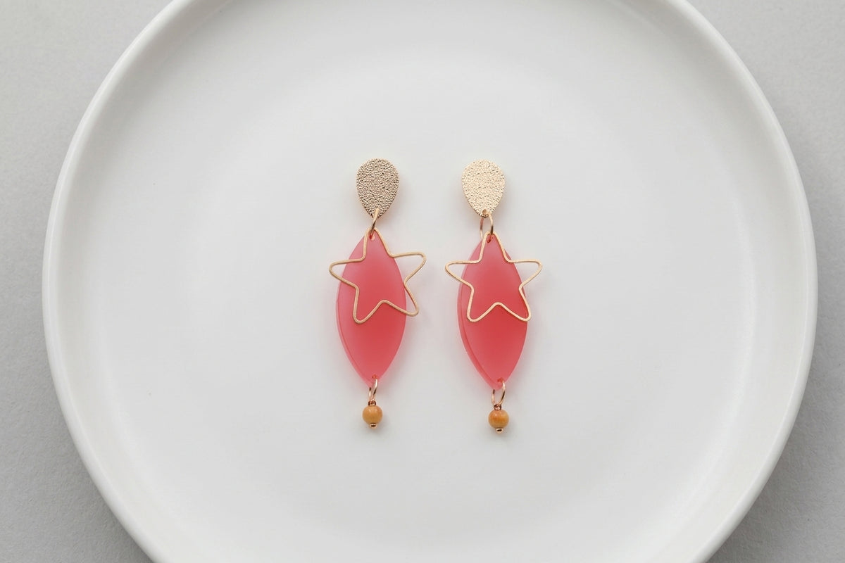 Pink Nina star geometric dangle earrings arranged on a white plate
