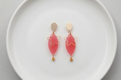Pink Nina star geometric dangle earrings arranged on a white plate