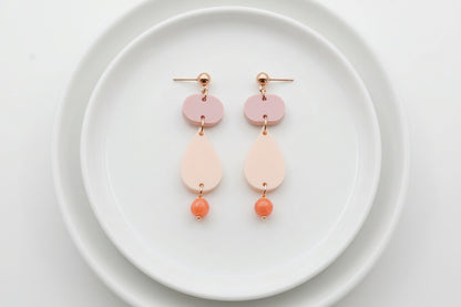 Beige Noor teardrop acrylic drop earrings arranged on a white plate