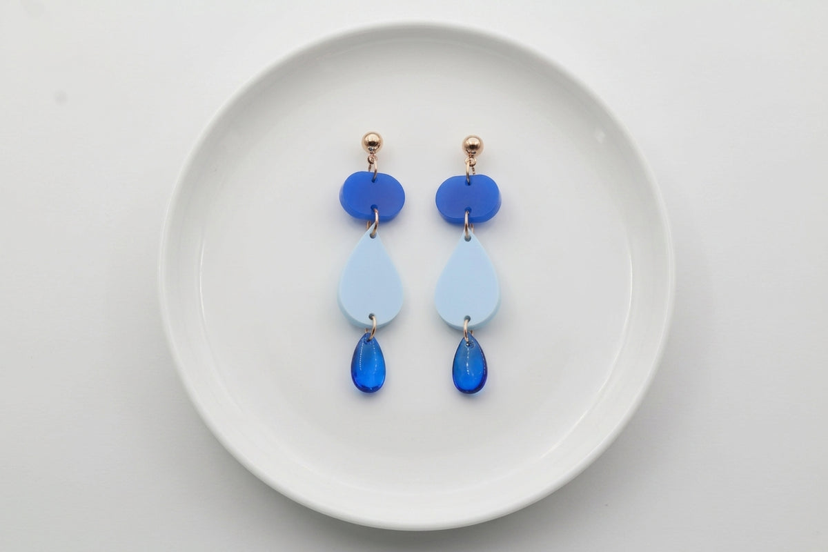 Blue Noor teardrop acrylic drop earrings arranged on a white plate