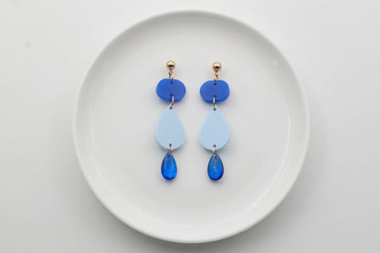 Blue Noor teardrop acrylic drop earrings arranged on a white plate