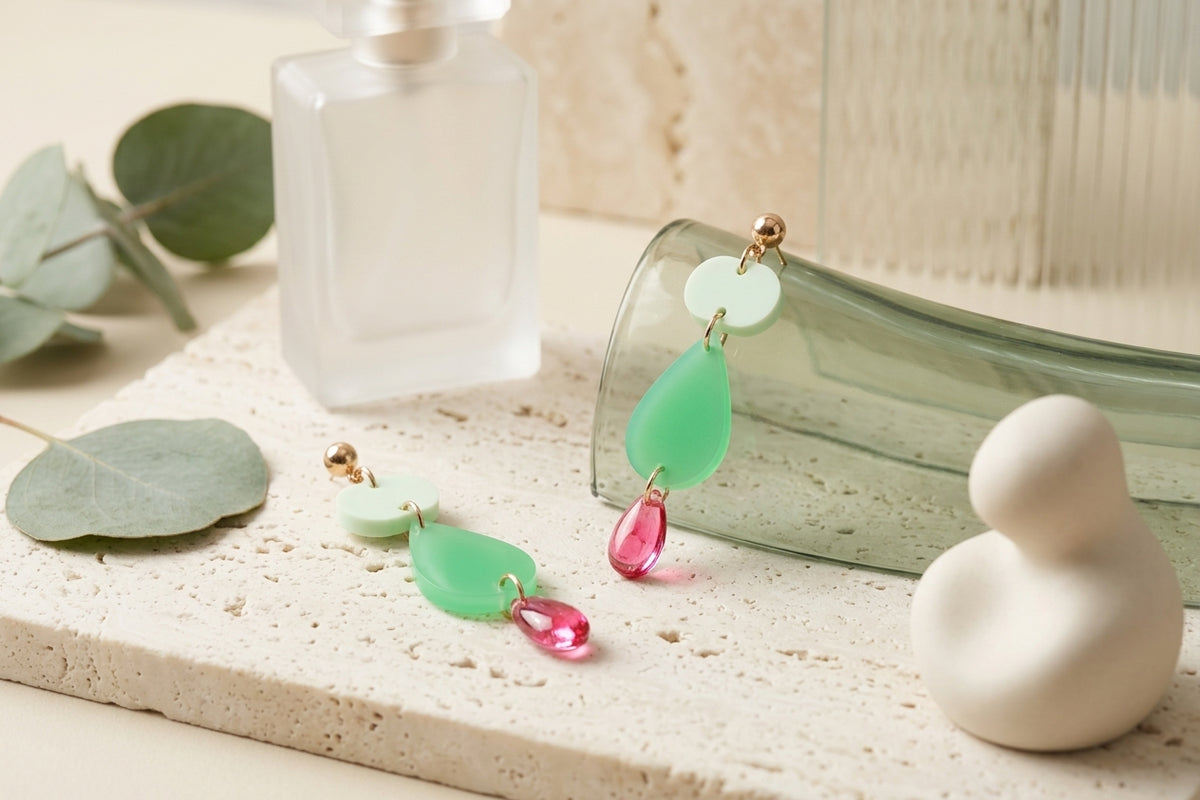 Green Noor teardrop acrylic drop earrings in a styled product setting