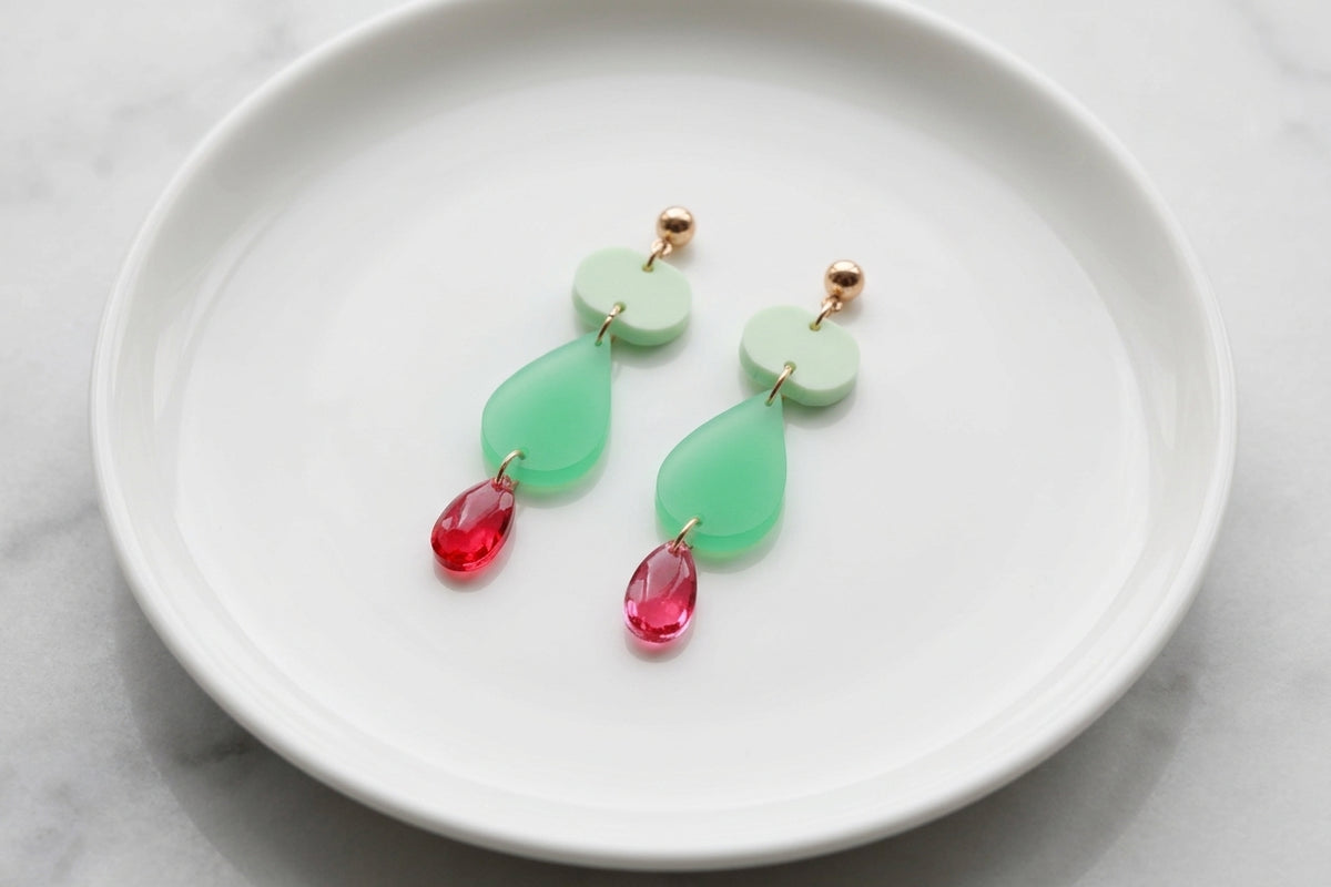 Green Noor teardrop acrylic drop earrings arranged on a white plate