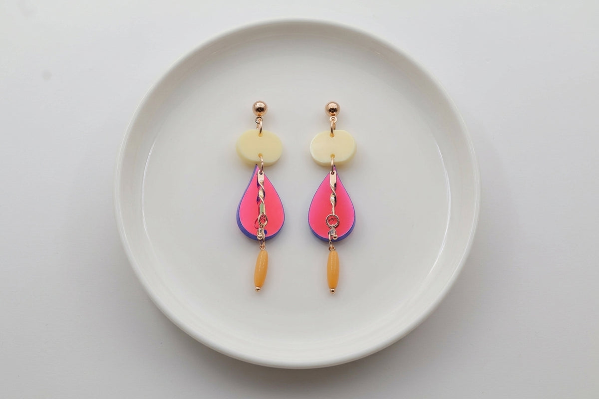 HB Noor teardrop acrylic drop earrings arranged on a white plate