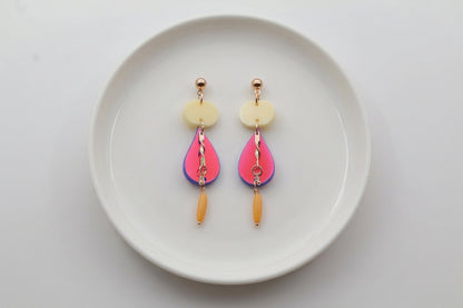 HB Noor teardrop acrylic drop earrings arranged on a white plate