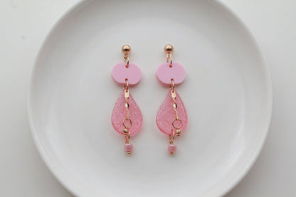 Pink Noor teardrop acrylic drop earrings arranged on a white plate