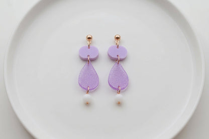 Purple Noor teardrop acrylic drop earrings arranged on a white plate