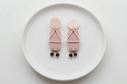 Beige Nora geometric rectangle dangle earrings arranged on a white plate