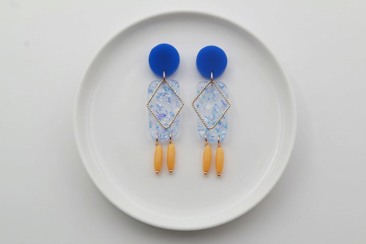 Blue Nora geometric rectangle dangle earrings arranged on a white plate
