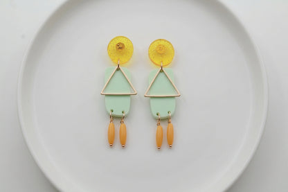 Green Nora geometric rectangle dangle earrings arranged on a white plate