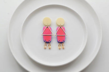 HB Nora geometric rectangle dangle earrings arranged on a white plate