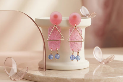 Pink Nora geometric rectangle dangle earrings in a styled product setting
