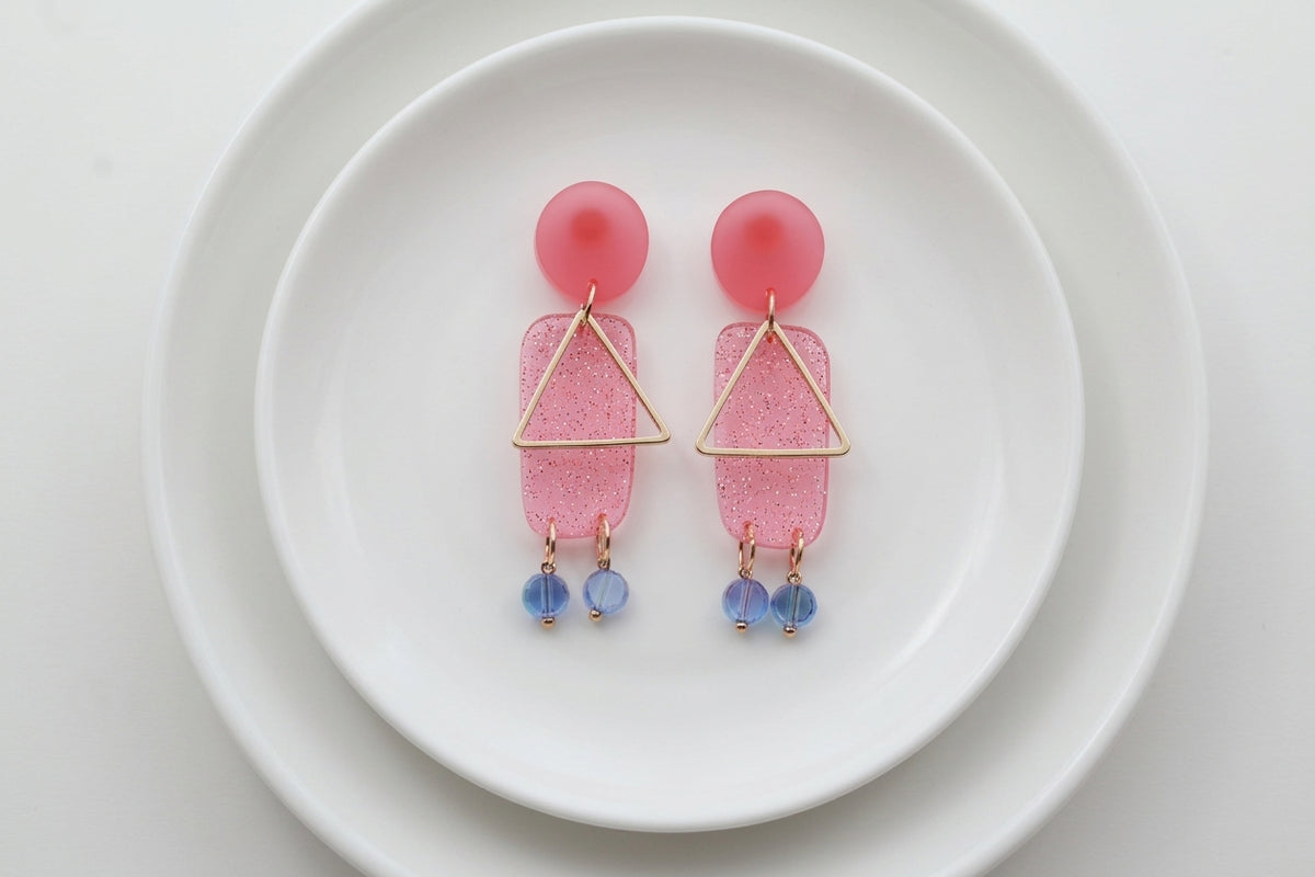 Pink Nora geometric rectangle dangle earrings arranged on a white plate