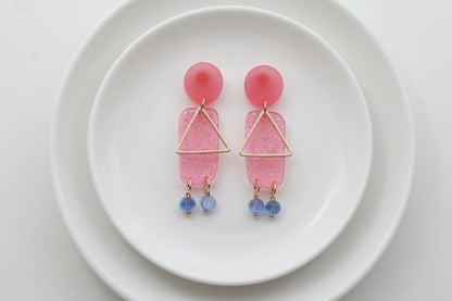 Pink Nora geometric rectangle dangle earrings arranged on a white plate