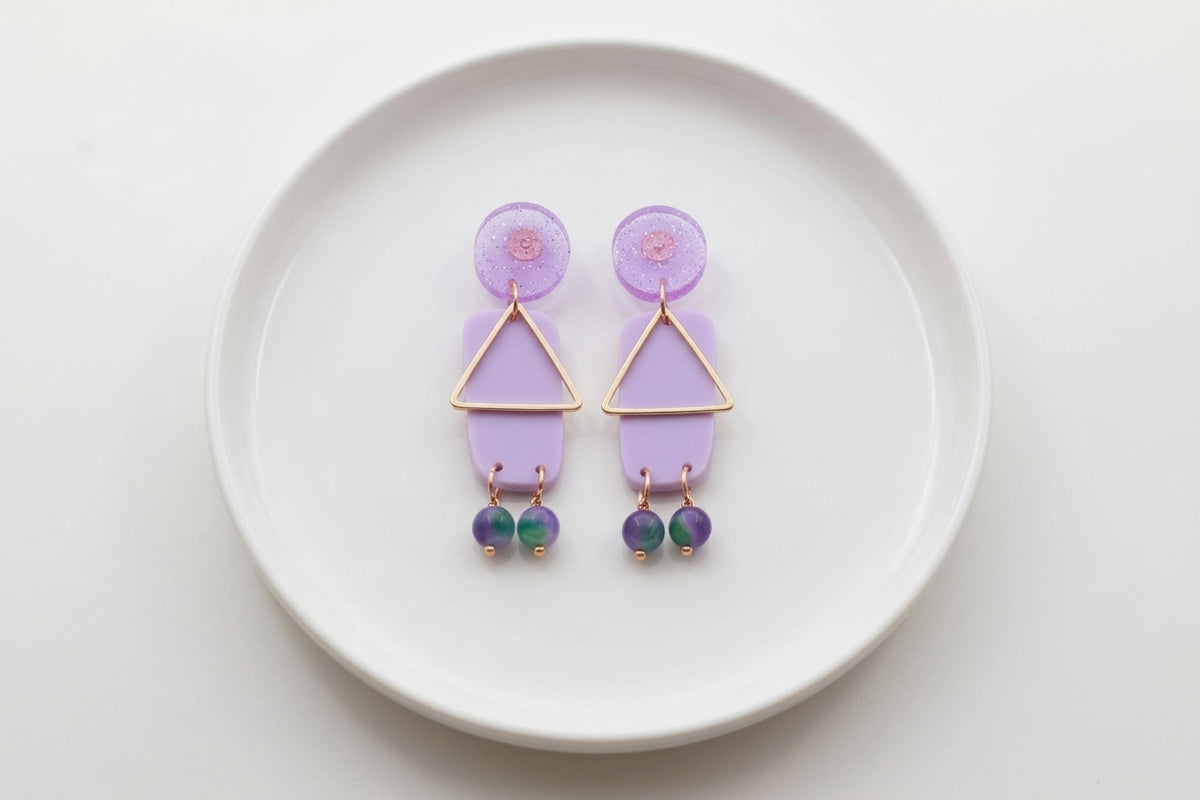 Purple Nora geometric rectangle dangle earrings arranged on a white plate