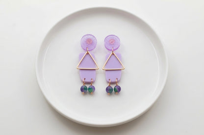 Purple Nora geometric rectangle dangle earrings arranged on a white plate
