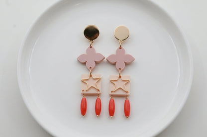 Beige Rose floral star drop earrings arranged on a white plate