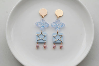 Blue Rose floral star drop earrings arranged on a white plate