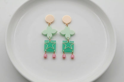 Green Rose floral star drop earrings arranged on a white plate