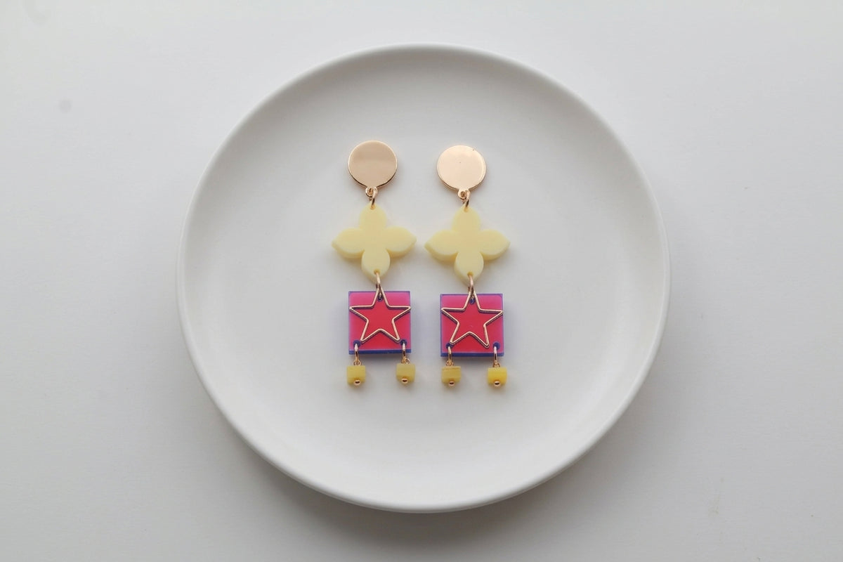 HB Rose floral star drop earrings arranged on a white plate