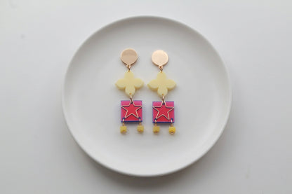 HB Rose floral star drop earrings arranged on a white plate