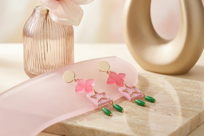 Pink Rose floral star drop earrings in a styled product setting